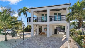 A two-story modern house with a covered front porch, a staircase leading to the upper level, and a driveway.