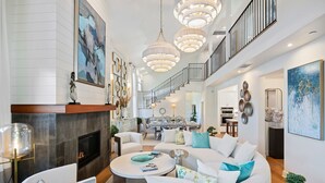 A spacious living room with a fireplace, a dining area, and a staircase leading to an upper level. - Lighthouse Dreams - Mesa Stunner Near the Beach (Santa Barbara)