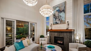 A modern living room with a fireplace, large windows, and a dining area. - Lighthouse Dreams - Mesa Stunner Near the Beach (Santa Barbara)