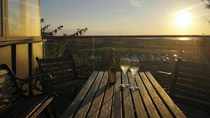 En balkon med et træbord, to vinglas og en vinflaske.