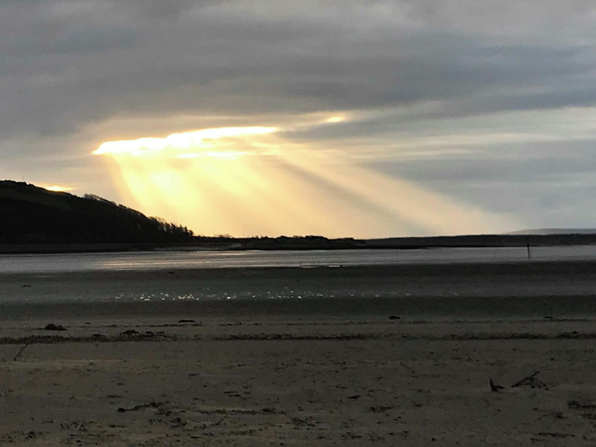 En strand med en bred sandremsa och ett lugnt vattenområde.