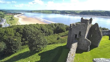 Ruinas de un castillo con vistas a un río y una playa.