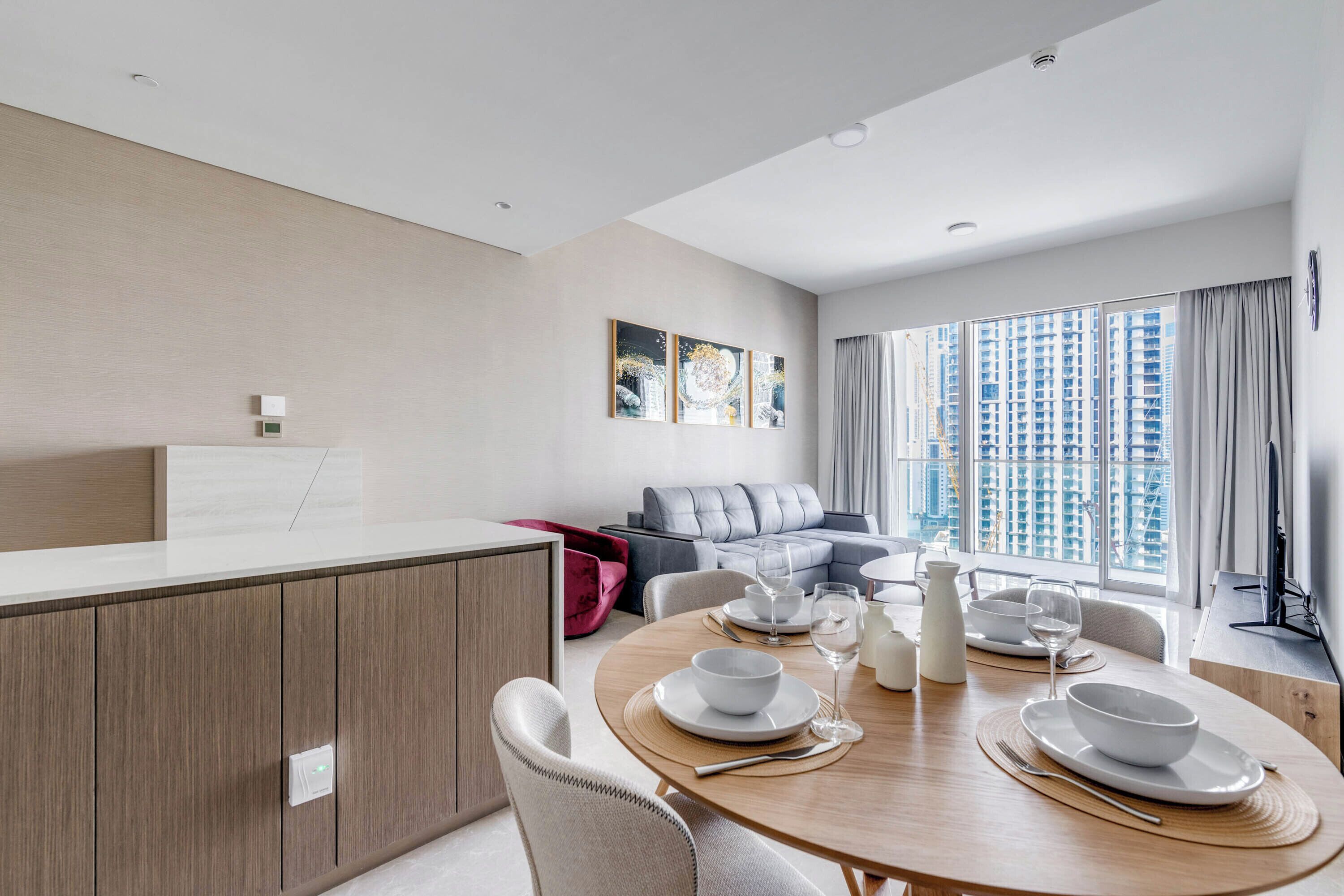 Een moderne woonkamer met een eethoek, een grijze bank en uitzicht op wolkenkrabbers.