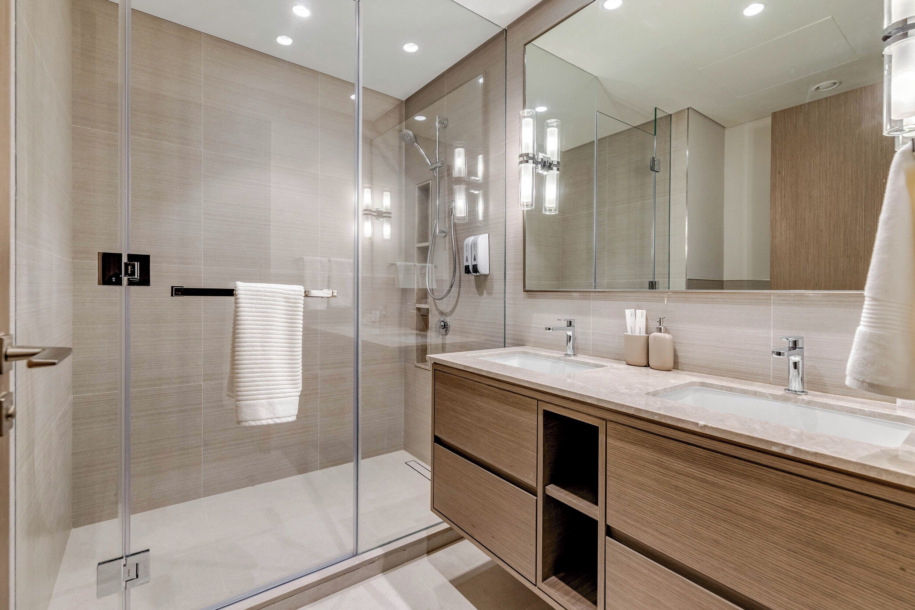 Une salle de bain moderne avec une douche en verre, un grand miroir et un meuble-lavabo en bois.