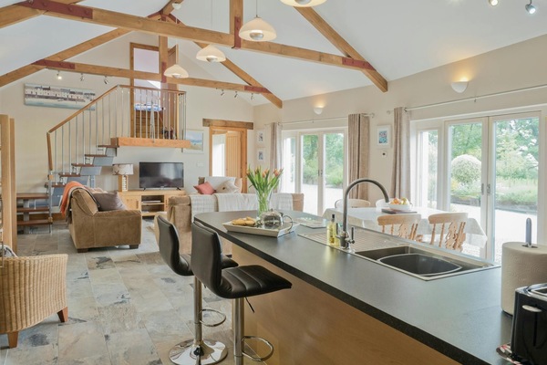 Open plan kitchen/living room: breakfast bar with sink and two bar stools