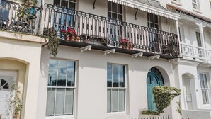 Edifici de dues plantes amb un balcó, façana blanca i diverses finestres.