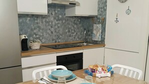 Eine moderne Küche mit weißen Schränken, einer Granit-Arbeitsplatte und einem Esstisch, gedeckt mit blauen Tellern und weißen Stühlen.