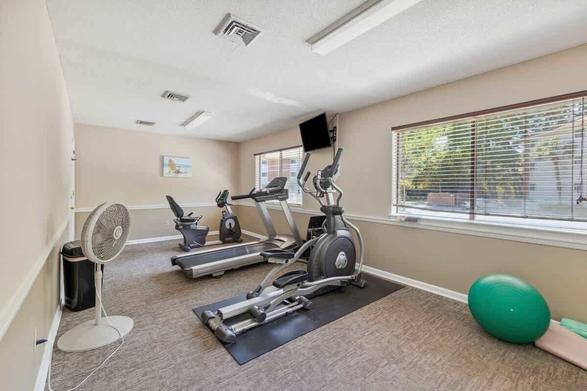 A gym with treadmills, an elliptical, a fan, and exercise balls.