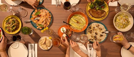 A group of people dining around a wooden table with various dishes and drinks.