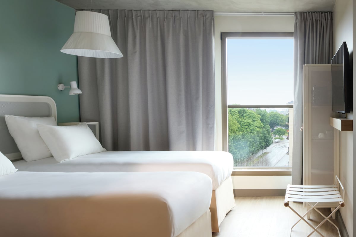 Een hotelkamer met twee bedden, een televisie en een raam met uitzicht.