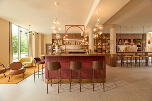 Un espace bar moderne doté d’un comptoir central, de tabourets de bar et de luminaires suspendus.