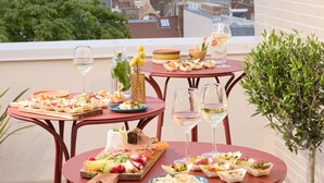 A balcony with a table set for a meal, overlooking a cityscape with buildings and a church tower. - OKKO Hotels Troyes Centre (Troyes)