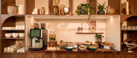 A buffet setup with various food items and a coffee machine.