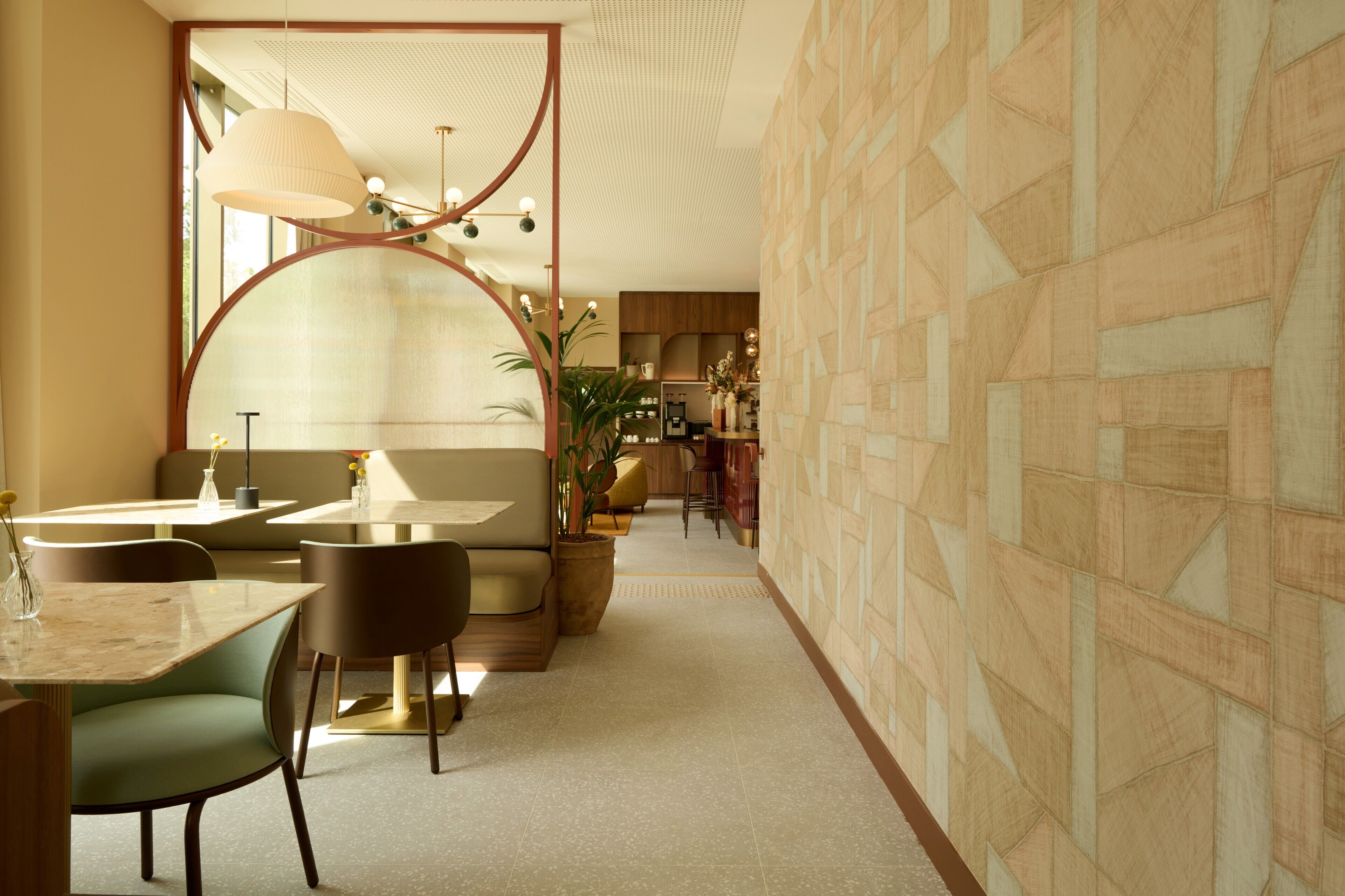 A modern interior with a dining area featuring round tables and chairs, a large mirror, and a patterned wall.
