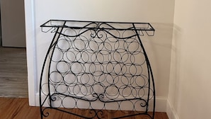 A metal table with a circular pattern, a painting of fruits and flowers on the wall, and a kitchen in the background. - Ideal location close to Texas Tech, University Medical Center, Covenant Hospital (Lubbock)