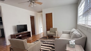 A living room with a flat-screen TV, two armchairs, a sofa, a wooden coffee table, and a patterned rug. - Ideal location close to Texas Tech, University Medical Center, Covenant Hospital (Lubbock)