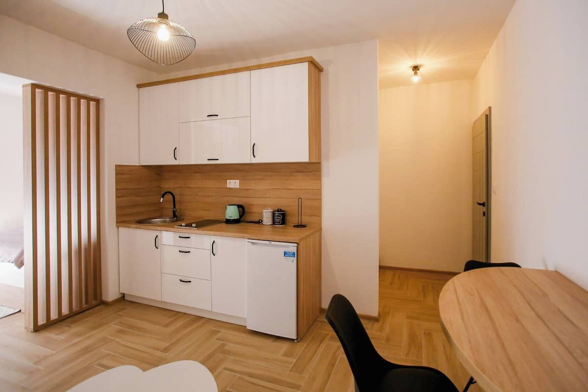 Une cuisine de taille réduite avec des meubles blancs, un plan de travail en bois et un seul évier.
