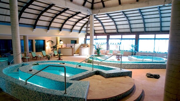 Une grande piscine intérieure à plusieurs niveaux, dotée d’un toit abrité.