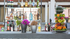 Un espace bar avec des étagères remplies de bouteilles d’alcool et un présentoir de fruits.