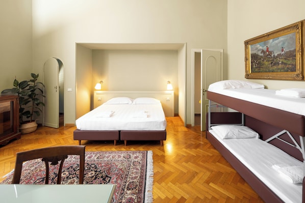 Un dormitorio con cama doble, literas, escritorio y una silla.
