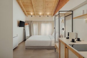 A modern bedroom with a wooden ceiling, a bed, a TV, a desk with a laptop, and a mirror. - 12 Pyles Living History (Ioannina)