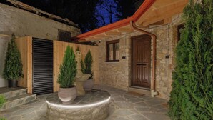 Un patio de piedra con puerta de madera, plantas en macetas y un banco de piedra.