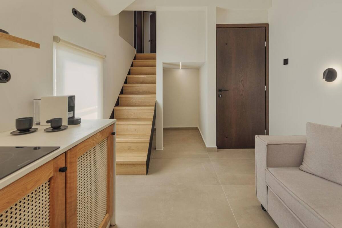 Um interior moderno com área de cozinha, escada e sala de estar.