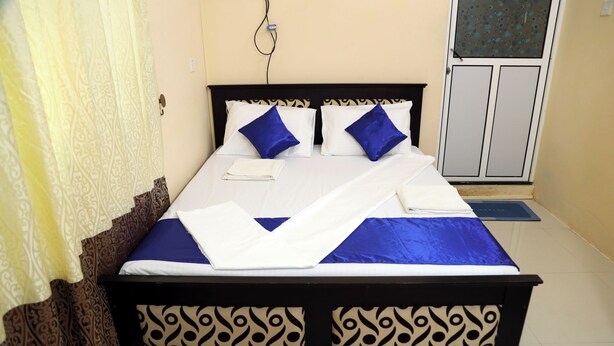 Una cama bien hecha con un cabecero estampado, una colcha azul y blanca y dos almohadas azules.