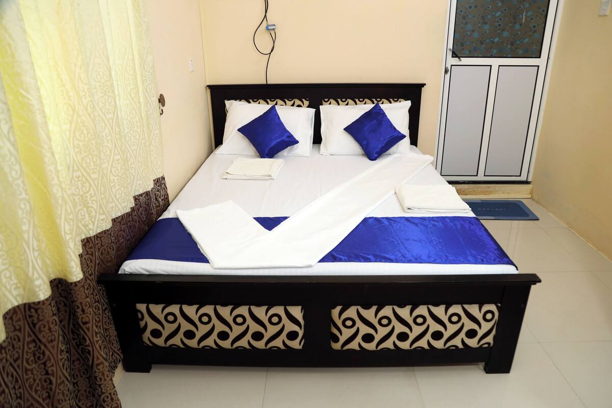 A neatly made bed with a patterned headboard, a blue and white bedspread, and two blue pillows.