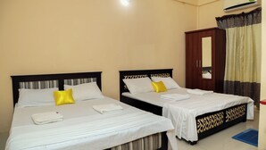 Habitación de hotel con dos camas, un armario y un equipo de aire acondicionado.
