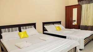 Dos camas individuales con sábanas blancas y almohadas amarillas, un armario de madera y un espejo.