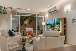 A modern living room with a sofa, armchairs, a coffee table, and a TV. - Modern 3-bedroom apartment with garden (Riyadh)