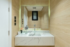 A bathroom with a marble sink, a mirror, and a small window. - Qurtoba big apartment all yours (Riyadh)