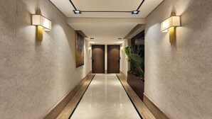 A modern hotel hallway with a marble floor, recessed lighting, and wall-mounted lamps. - Qurtoba big apartment all yours (Riyadh)