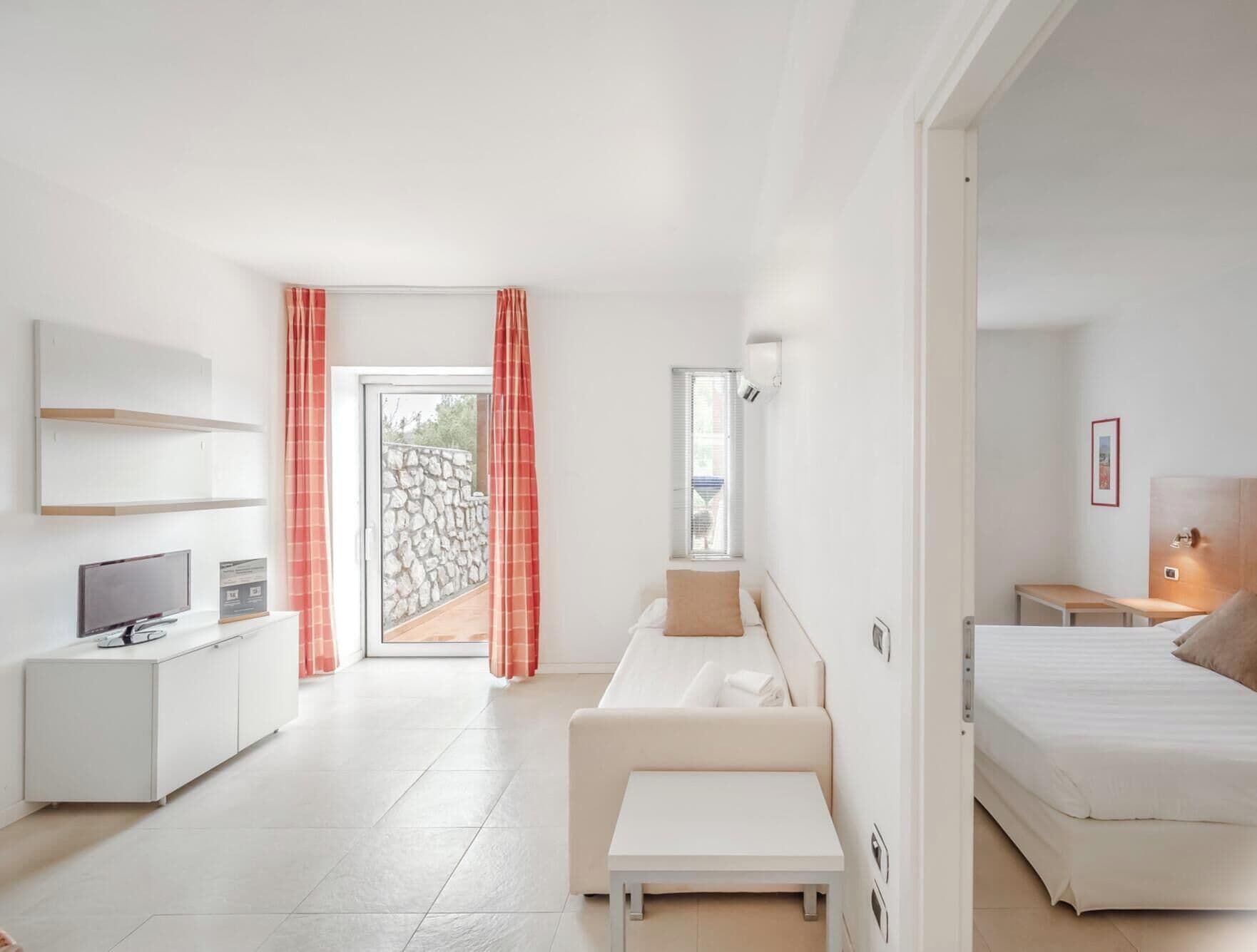 Ett modernt hotellrum med en säng, en soffa, en TV, ett skrivbord och ett badrum.