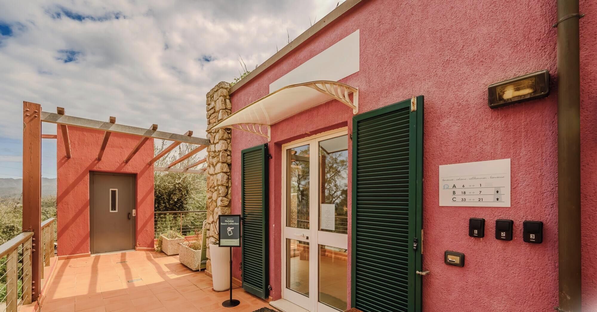 A hotel entrance with a stone pillar, a covered walkway, and a sign indicating room collection.