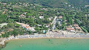 Vista aérea de un pueblo costero con playa, edificios residenciales y un estacionamiento.