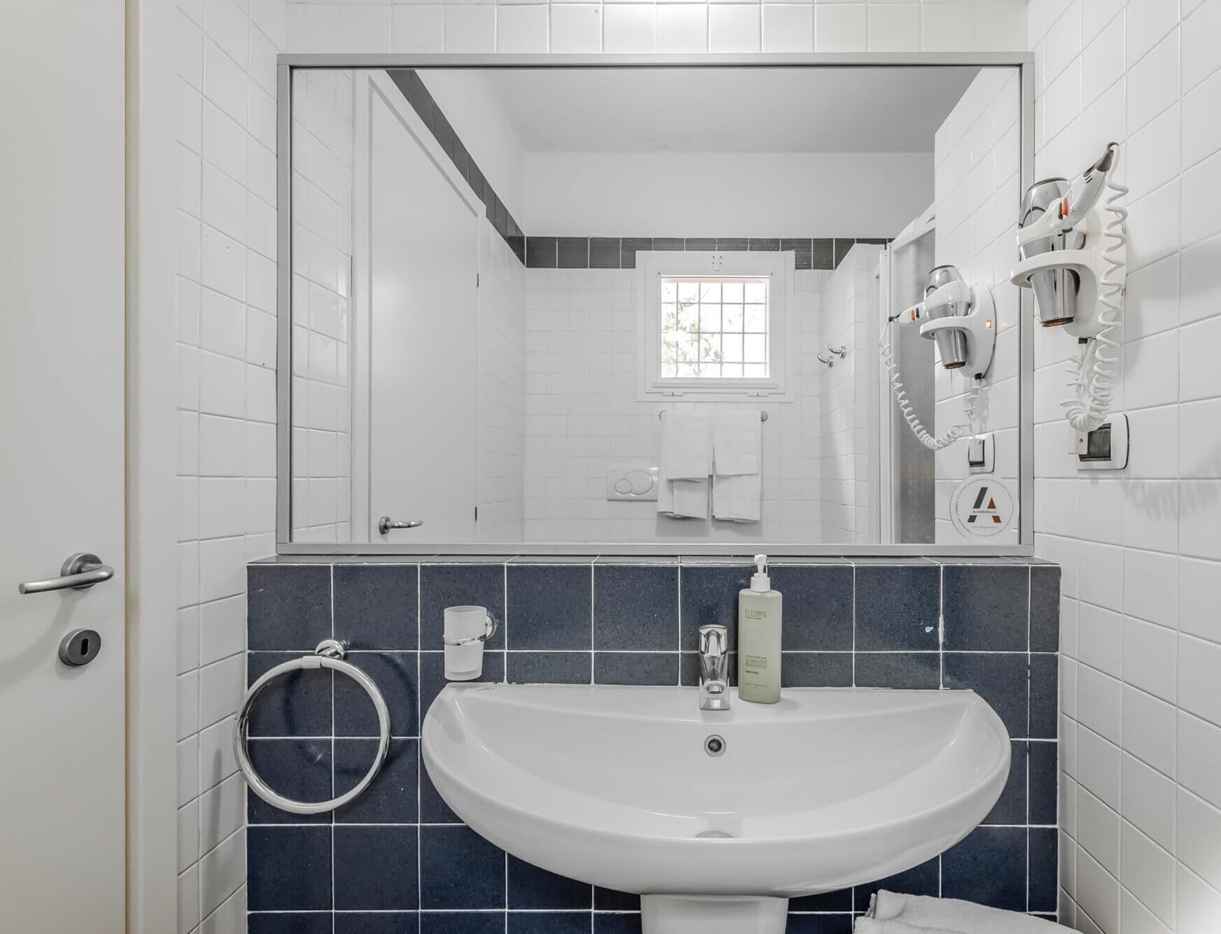 A bathroom with a white sink, a mirror, and a towel rack.