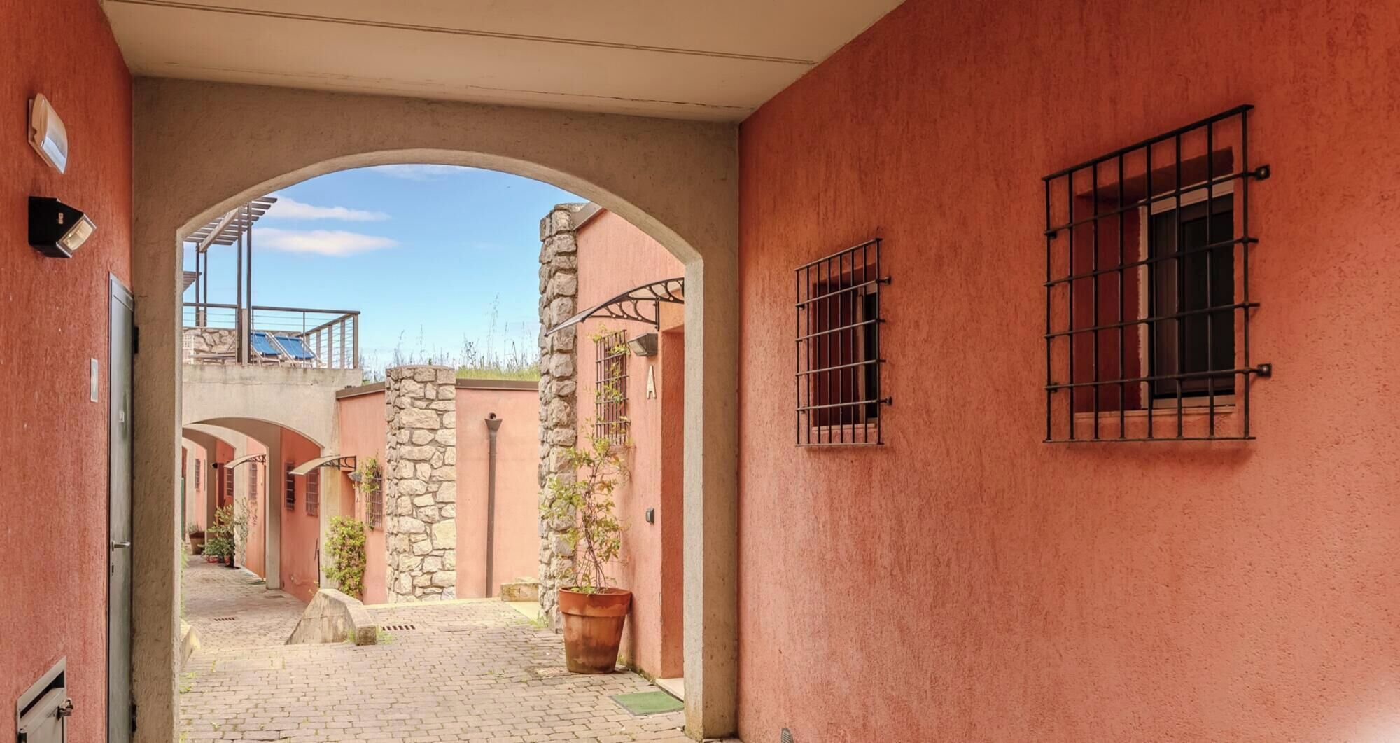 Un stretto vicolo con pilastri in pietra, portali ad arco e finestre con inferriate.