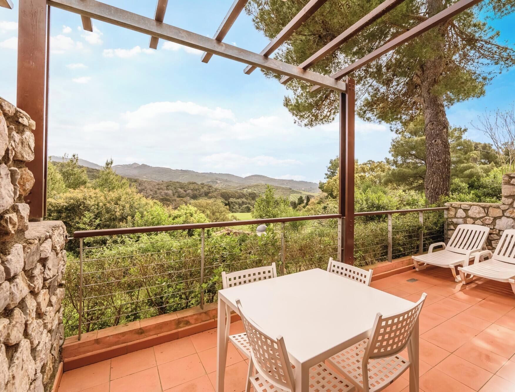 Une terrasse avec une table et des chaises, un mur en pierre et une vue sur la campagne.
