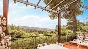 Una terraza con una mesa y sillas, un muro de piedra y vistas al campo.