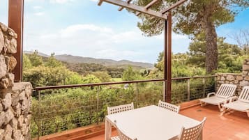 Une terrasse avec une table et des chaises, un mur en pierre et une vue sur la campagne.