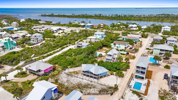 A coastal residential area with houses, a beach, and a pier.