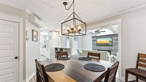 Un comedor con mesa de madera, cuatro sillas y una araña.