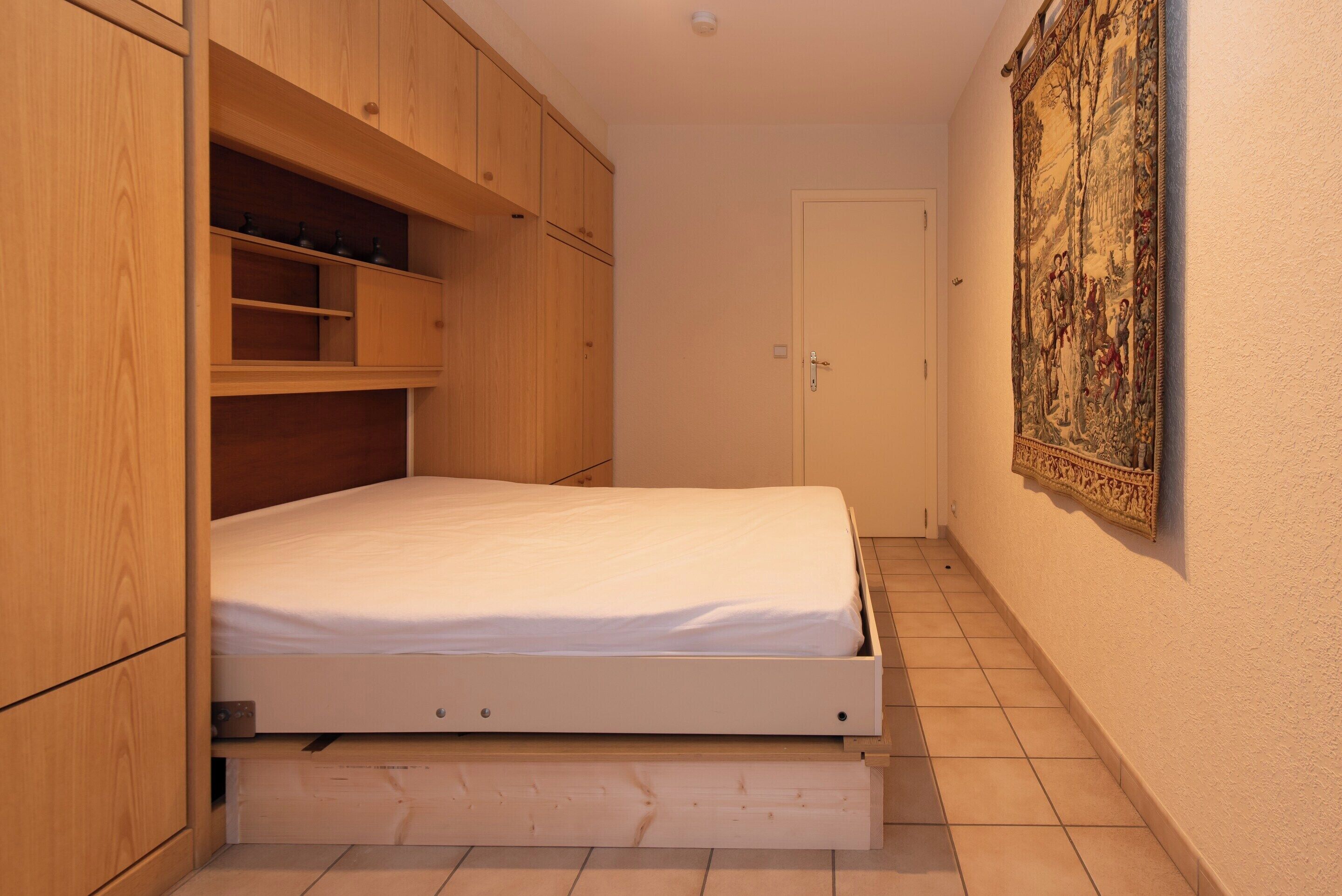 Un dormitorio con una cama, un armario de madera y un tapiz en la pared.