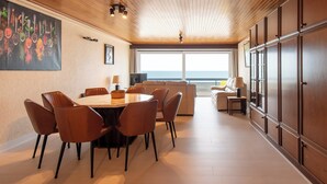 Un comedor moderno con una mesa redonda y sillas, un sofá, y vista al océano.