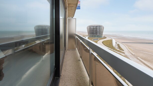 Un balcón con vista a la playa y un letrero que indica un restaurante.