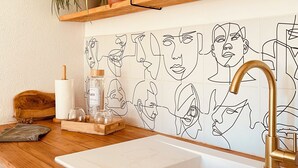 A kitchen with a wooden countertop, a sink, and a wall-mounted shelf with plants and decorative items. - Le Mas de San lou (Cabasse)