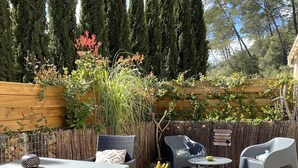 A patio area with a wooden table and chairs, a wicker sofa, and a small round table with a bowl. - Le Mas de San lou (Cabasse)