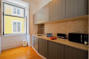 Una cocina con ventana, pileta, tostadora y basurero.